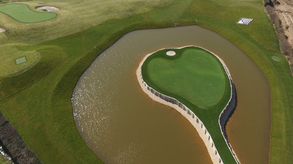 Oakley Aerial view of a vibrant green synthetic grass island in a natural pond on a golf course