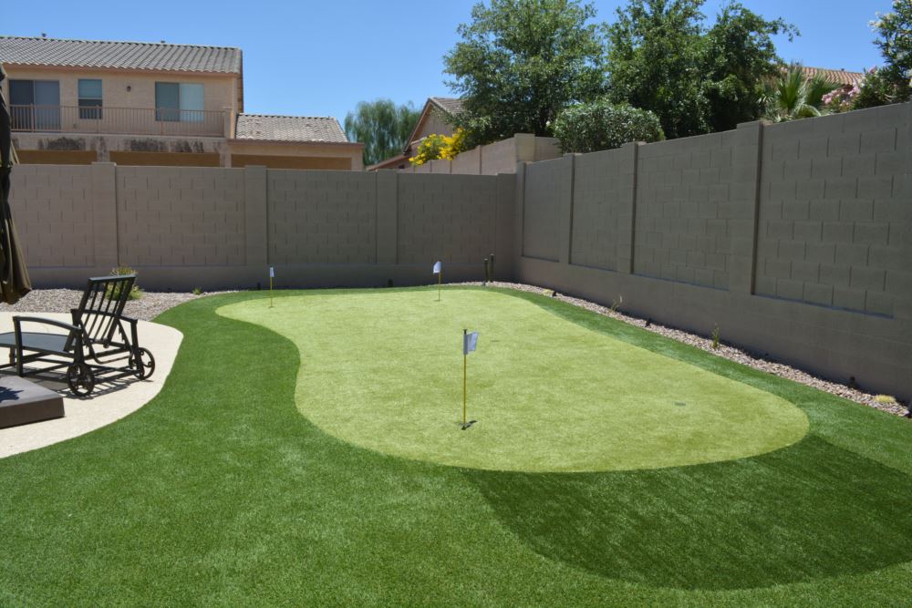 Custom backyard putting greens featuring smooth artificial turf practice areas with multiple flagsticks, designed for at-home golf training and low-maintenance outdoor living.